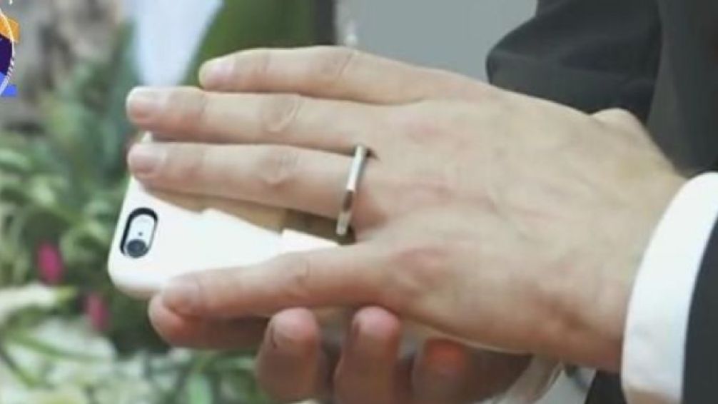Boda atípica. El novio con el anillo que lo une a su smartphone.